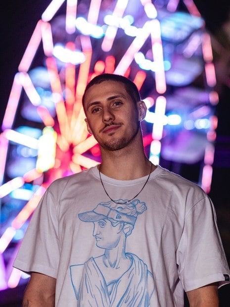 homem de camiseta branca com uma roda gigante ao fundo