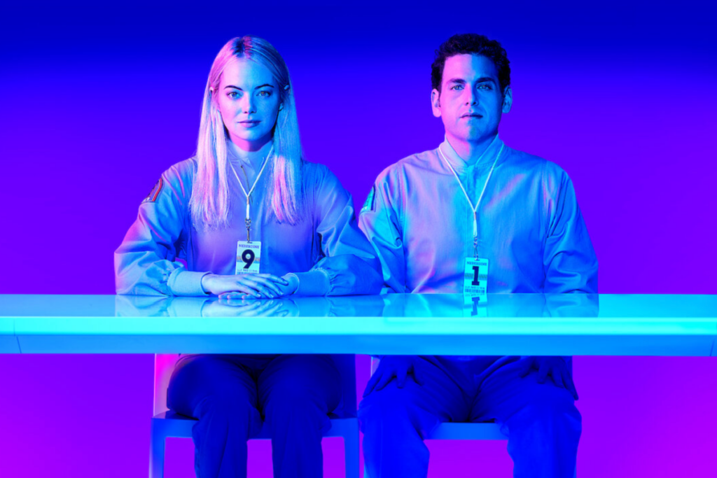 Cena da produção "Maniac", com Jonah Hill e Emma Stone sentados lado a lado em um ambiente futurista